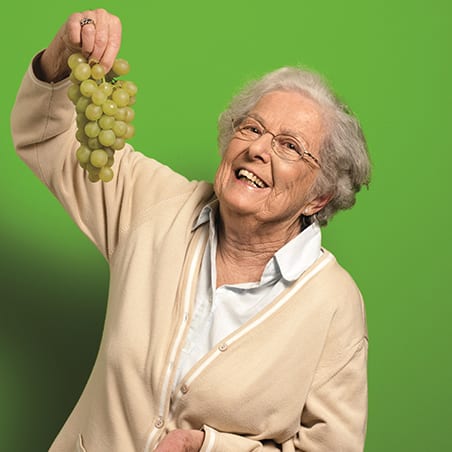 GEMEINSAM G´SUND GENIESSEN Image ältere Frau mit Weintraube - Rezepte für eine gesunde Ernährung